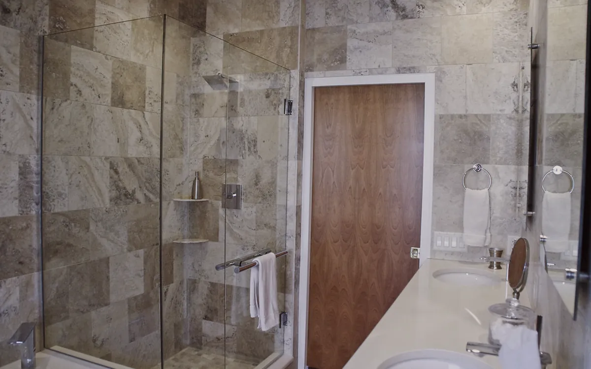 Baño terminado con ducha, revestimiento de piedra y grifería